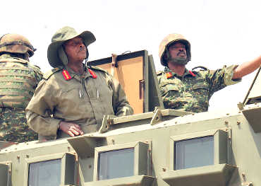 Museveni inspecting his troops from an armoured carrier with guidance from Brig. Muhanga