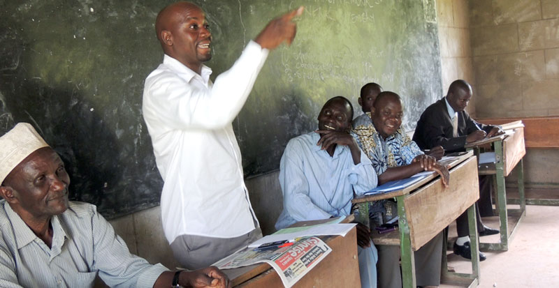 Katongole addressing a parents' meeting at Amir Ntambi memorial S.S. On his right is Hajj Muhammad Serunjogi, along with other leaders of the school