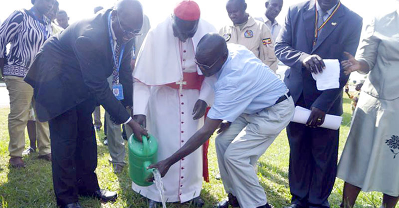 Makuza and Cardinal Wamala watering a tree that the Cardinal planted at Entebbe Airport